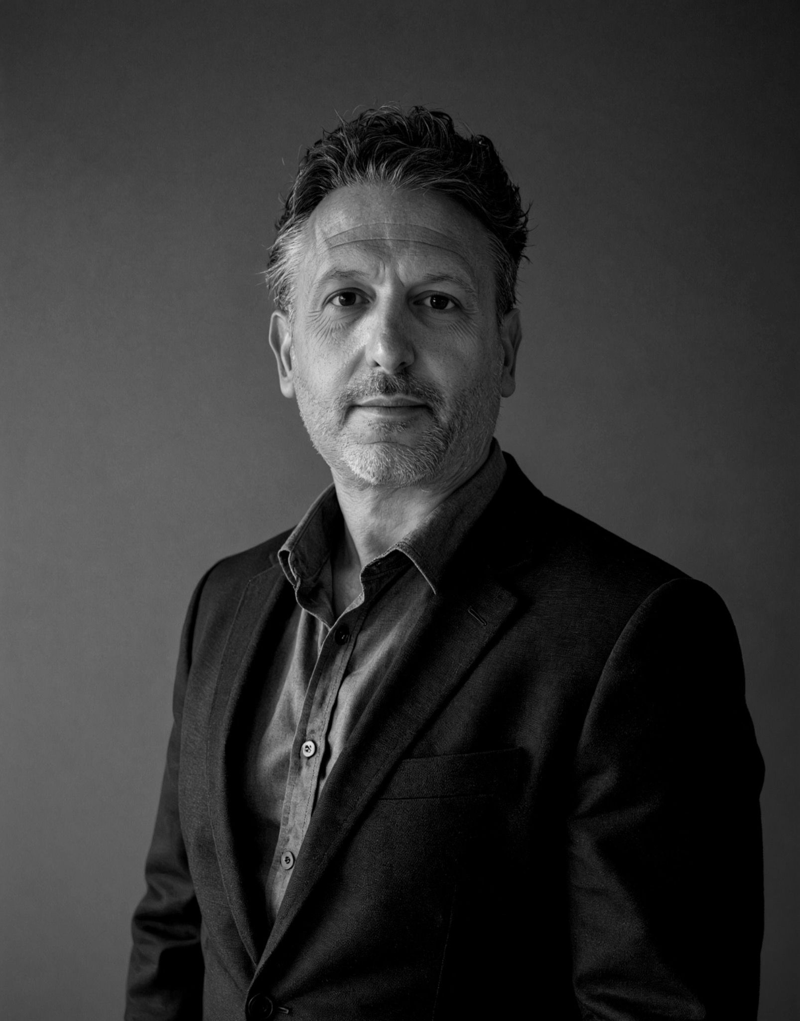 Andrew Mark Klapper photographed against a plain graphite background.