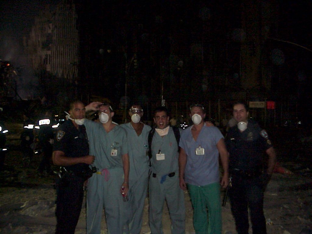 Bellevue Hospital plastic surgery and medical response team at the World Trade Center site, New York, 2001: seven people in scrubs and police uniform wearing respirators, photographed at night.